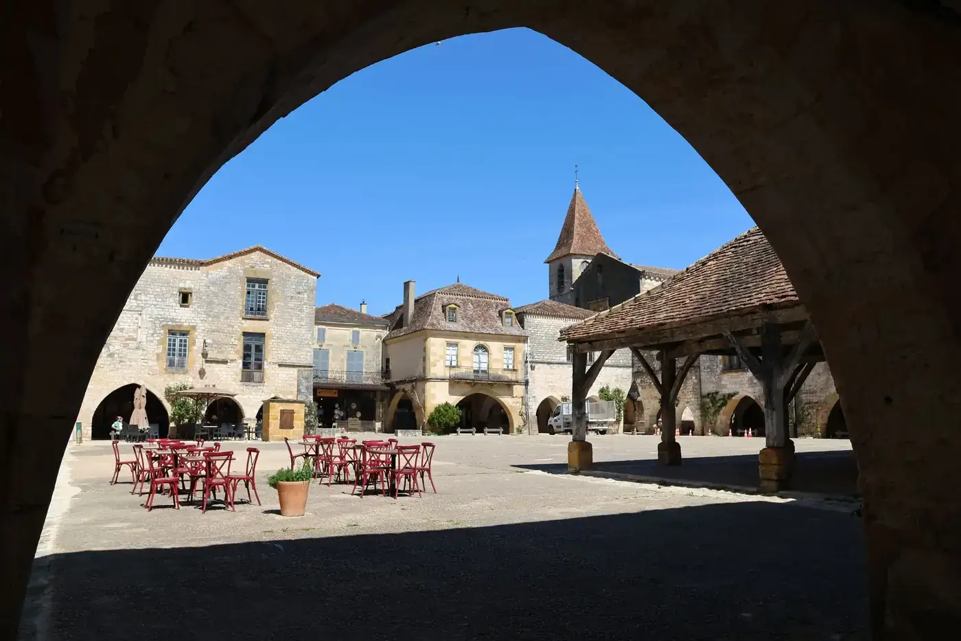 Beautiful view of Monpazier village square with historic architecture under a blue sky.