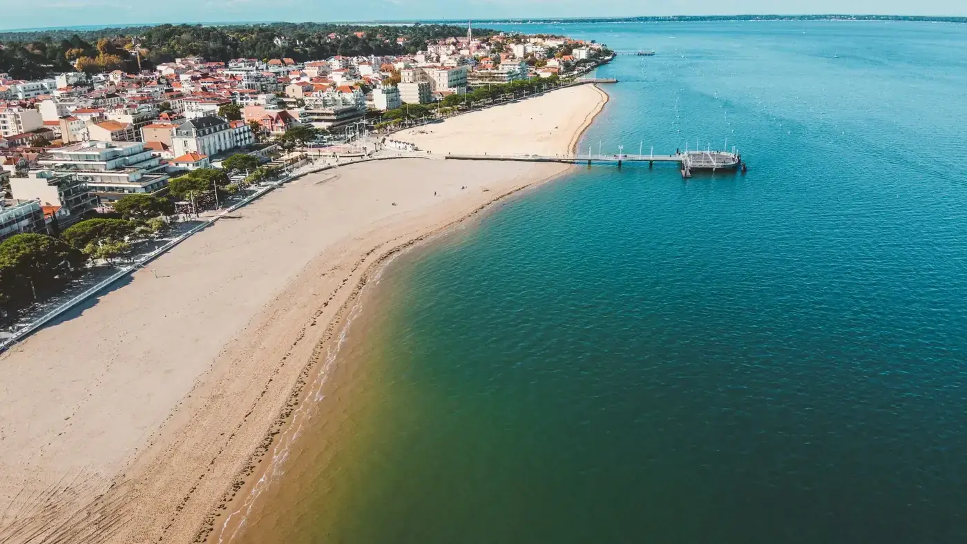 A stunning aerial view of Arcachon beach and urban landscape with clear skies and vibrant waters.