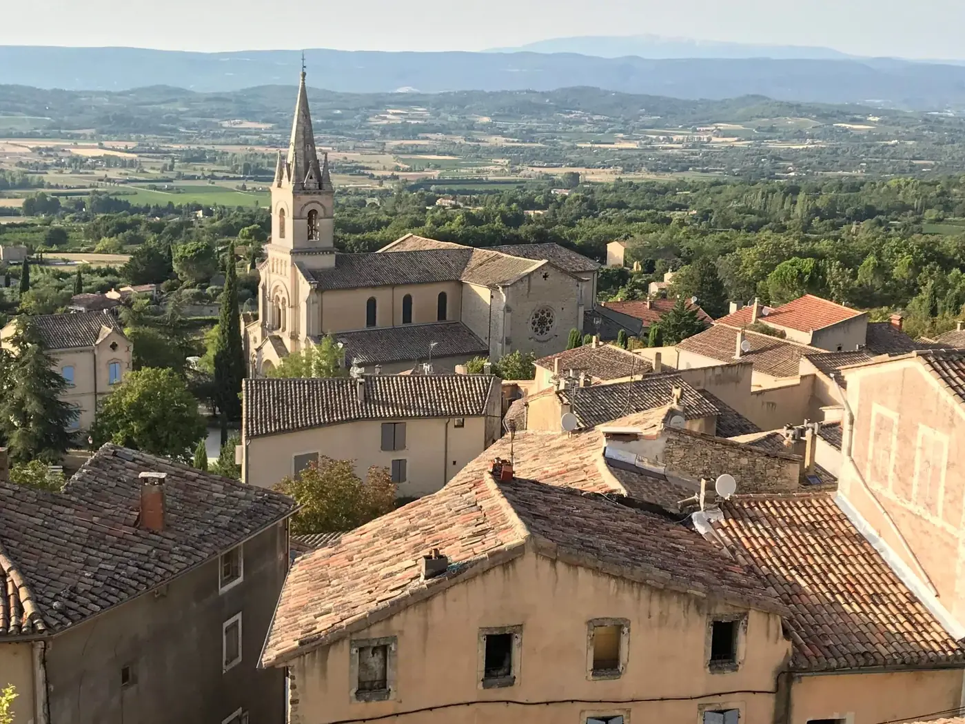 A picturesque view of Saignon's historic church and surrounding countryside in Provence, France.