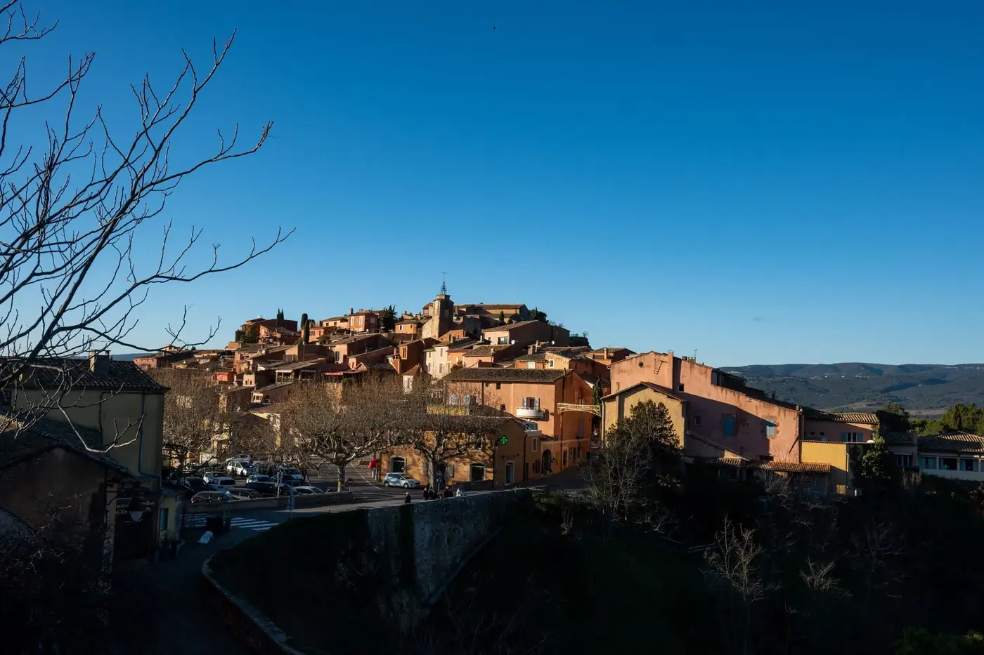 Picturesque view of Roussillon village in Provence with traditional ochre-colored buildings under a clear blue sky.