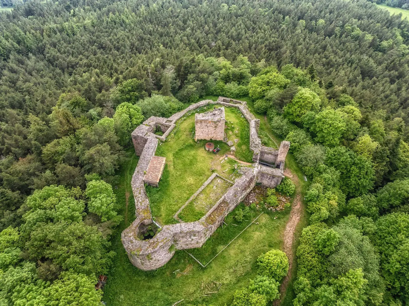 Drone shot of the historic Château des Hohnack ruins surrounded by dense forest in Alsace, France.