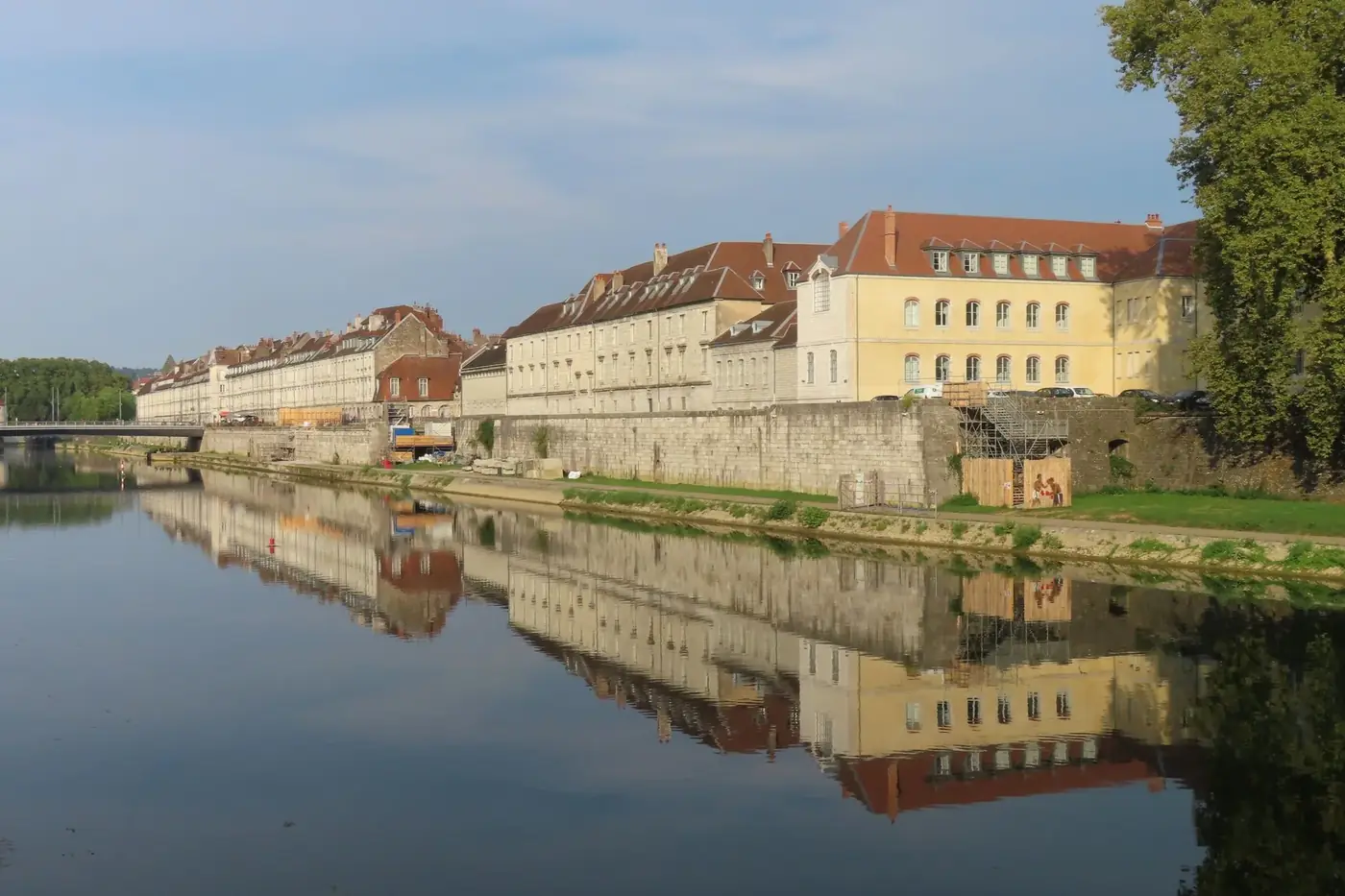 Charming old buildings reflected on a calm river in a historic cityscape.