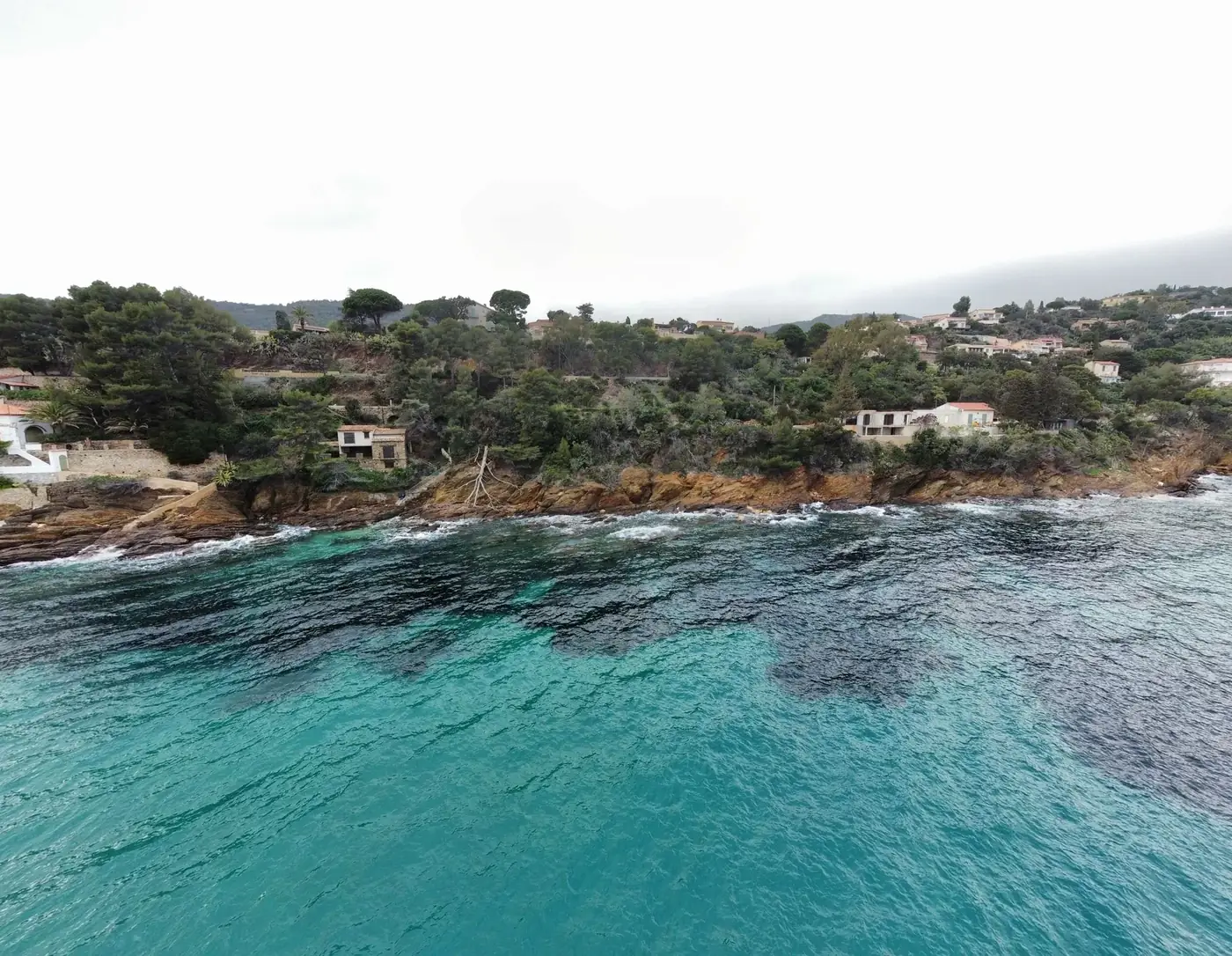 A stunning aerial view of a coastal village in France with azure waters and lush greenery.