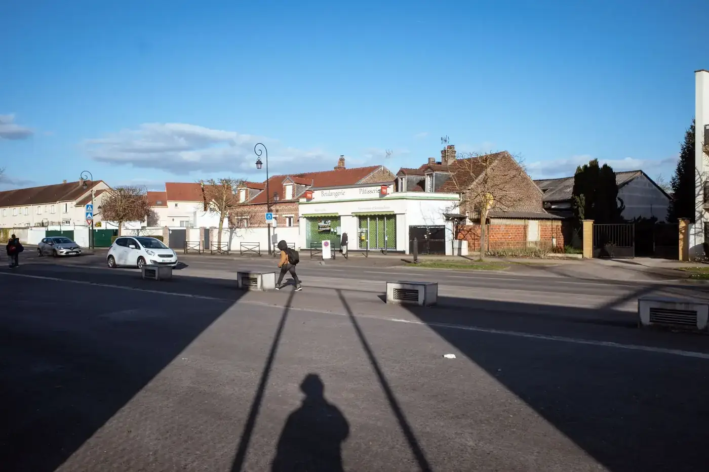 Tranquil suburban street scene in Compiègne, Hauts-de-France, France with people and cars.