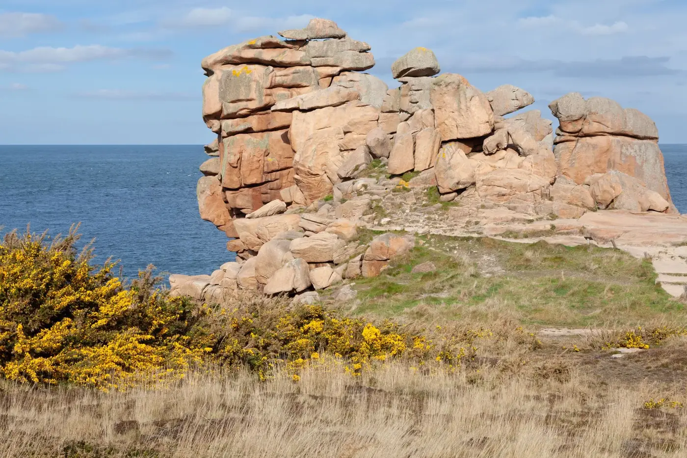Stunning granite cliffs and coastal landscape at Plougrescant, Brittany, France under bright blue skies.
