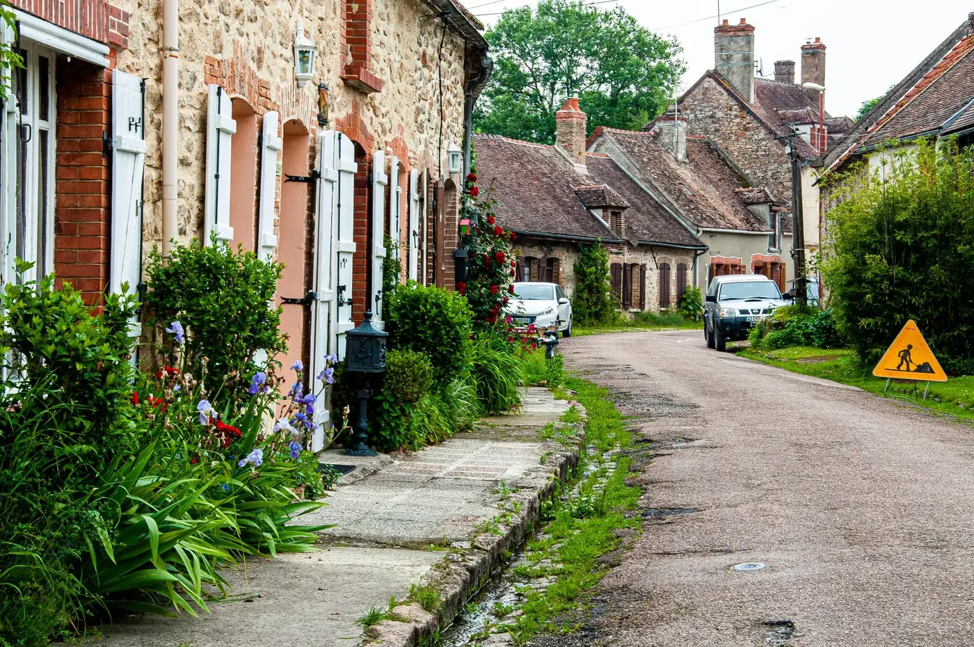 Quaint street view in Nogent-sur-Seine, showcasing stone houses and lush greenery.