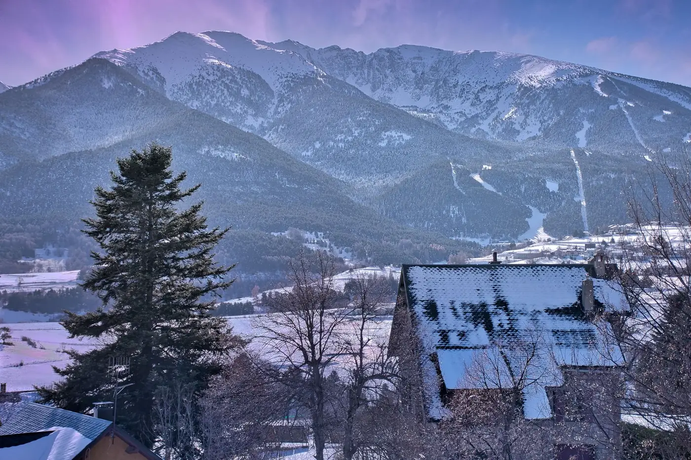 Breathtaking view of snow-covered mountains and a quaint alpine village in winter.