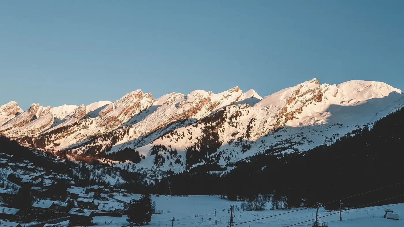 Breathtaking winter landscape of snowy mountains in La Clusaz, France during sunrise.