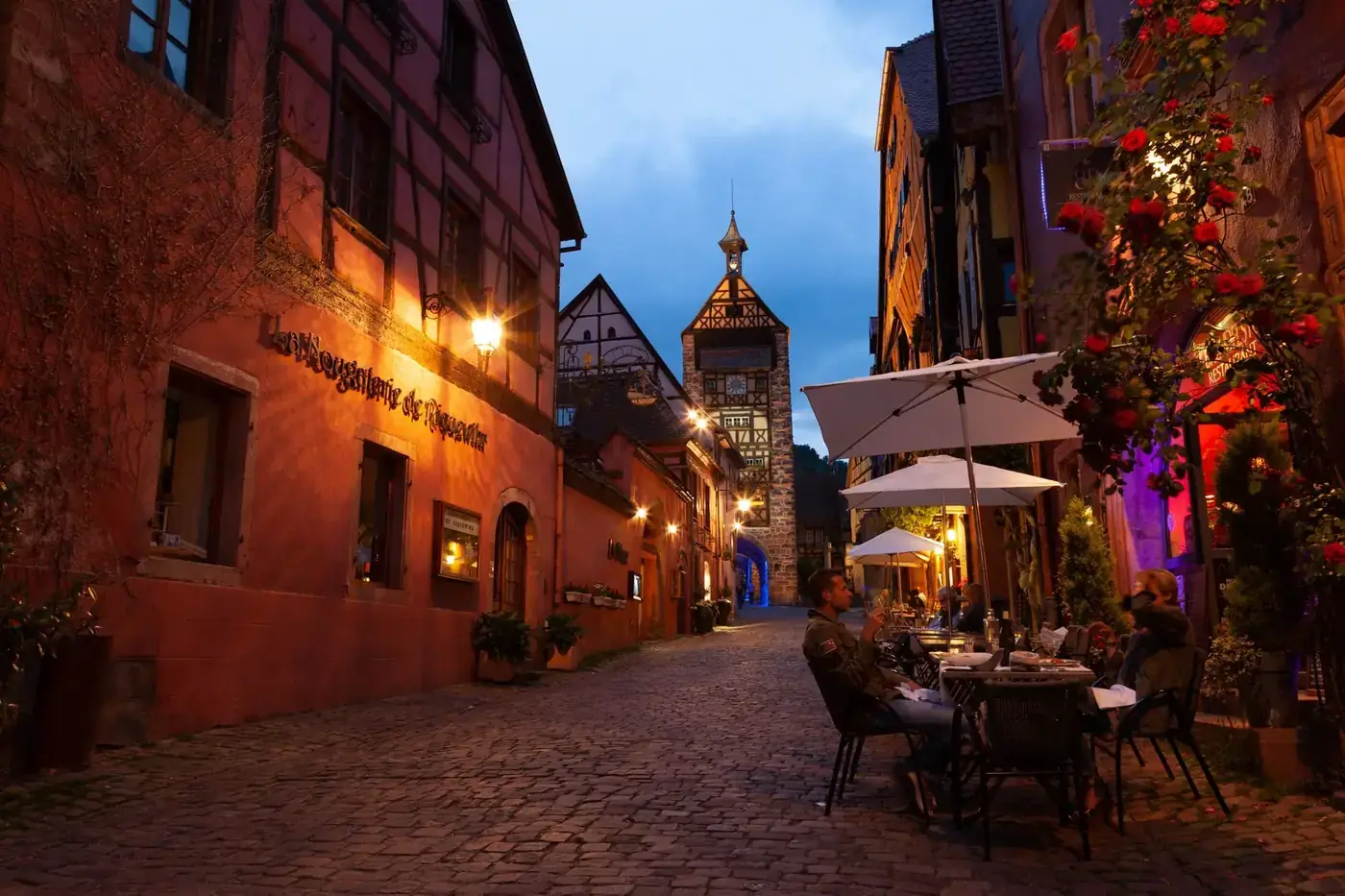 A picturesque evening scene from Riquewihr, France, showcasing cobblestone streets and medieval architecture.