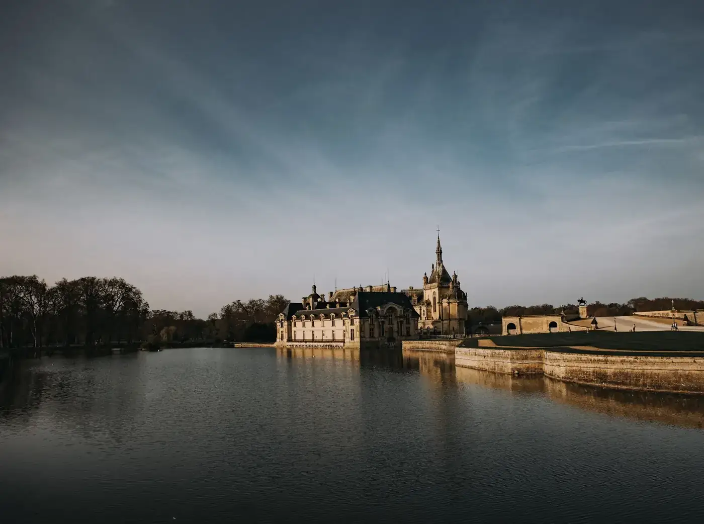 Scenic view of Château de Chantilly with calm waters and clear sky in France.