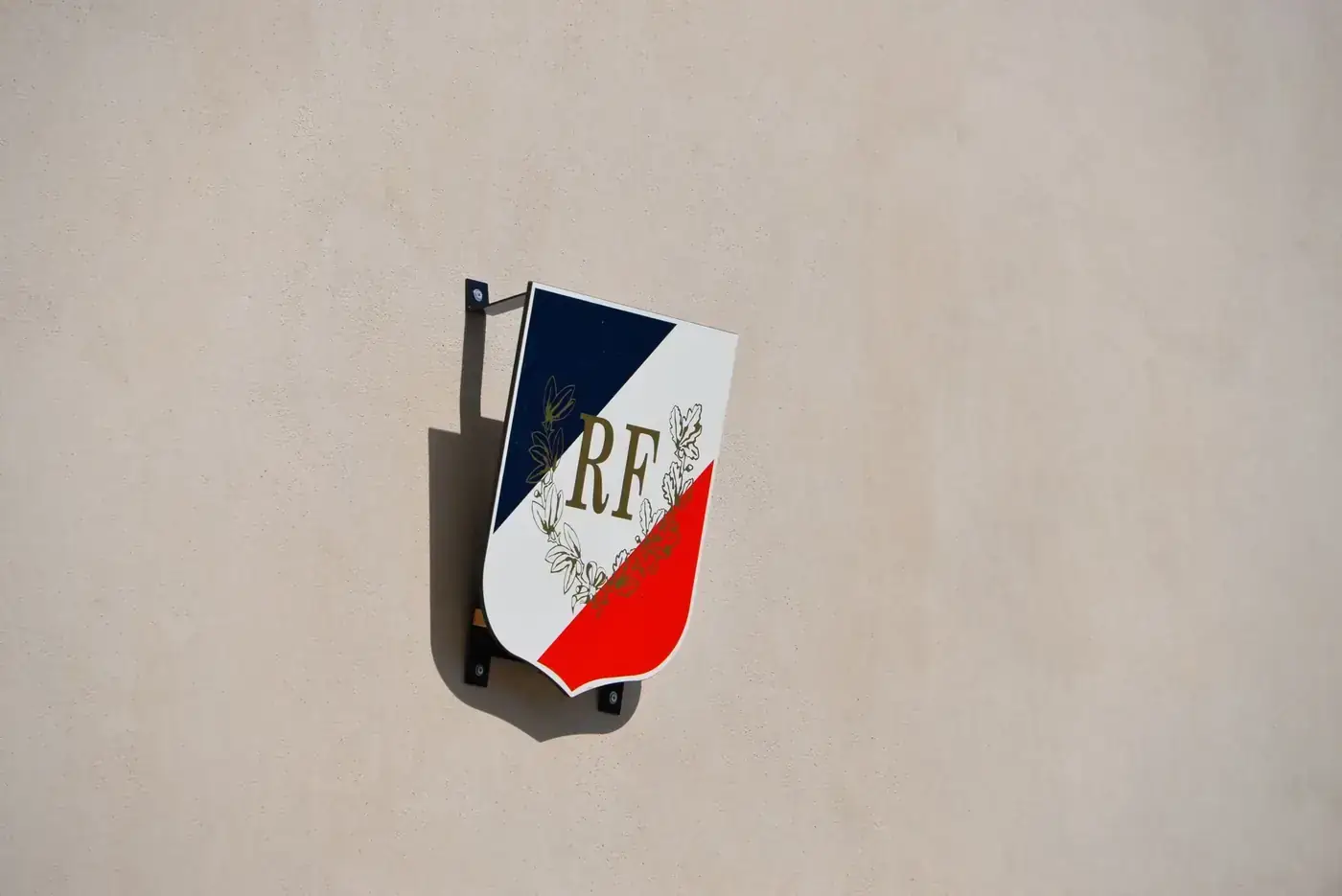 French Republic emblem mounted on a beige building wall, symbolizing national pride.