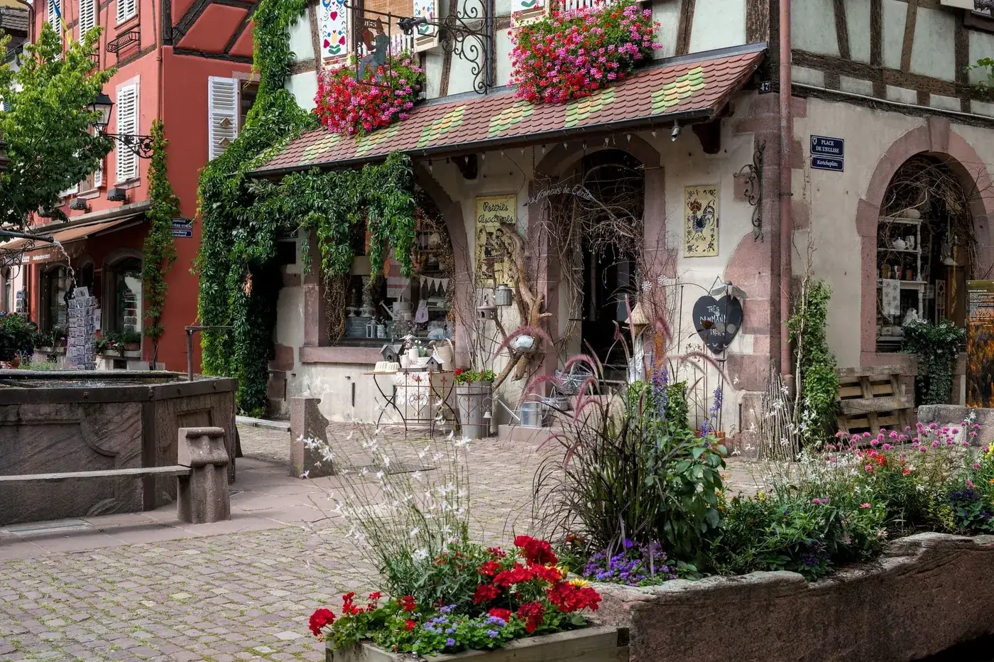 Picturesque street in Kaysersberg, France with colorful blooms and half-timbered houses.