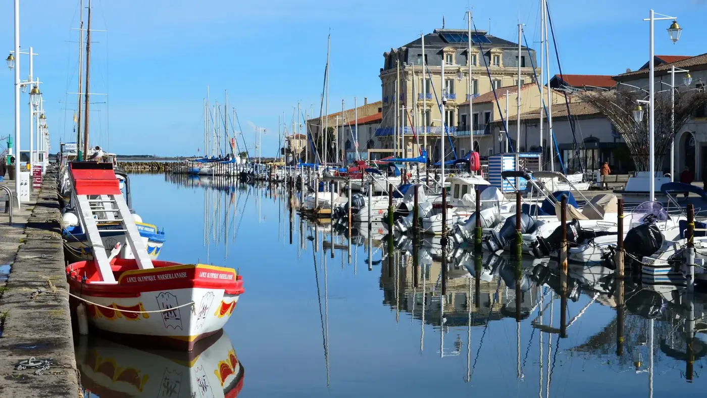 Beautiful sunny day in Marseillan Harbor, Occitanie, France. Vibrant boats reflect on calm waters.