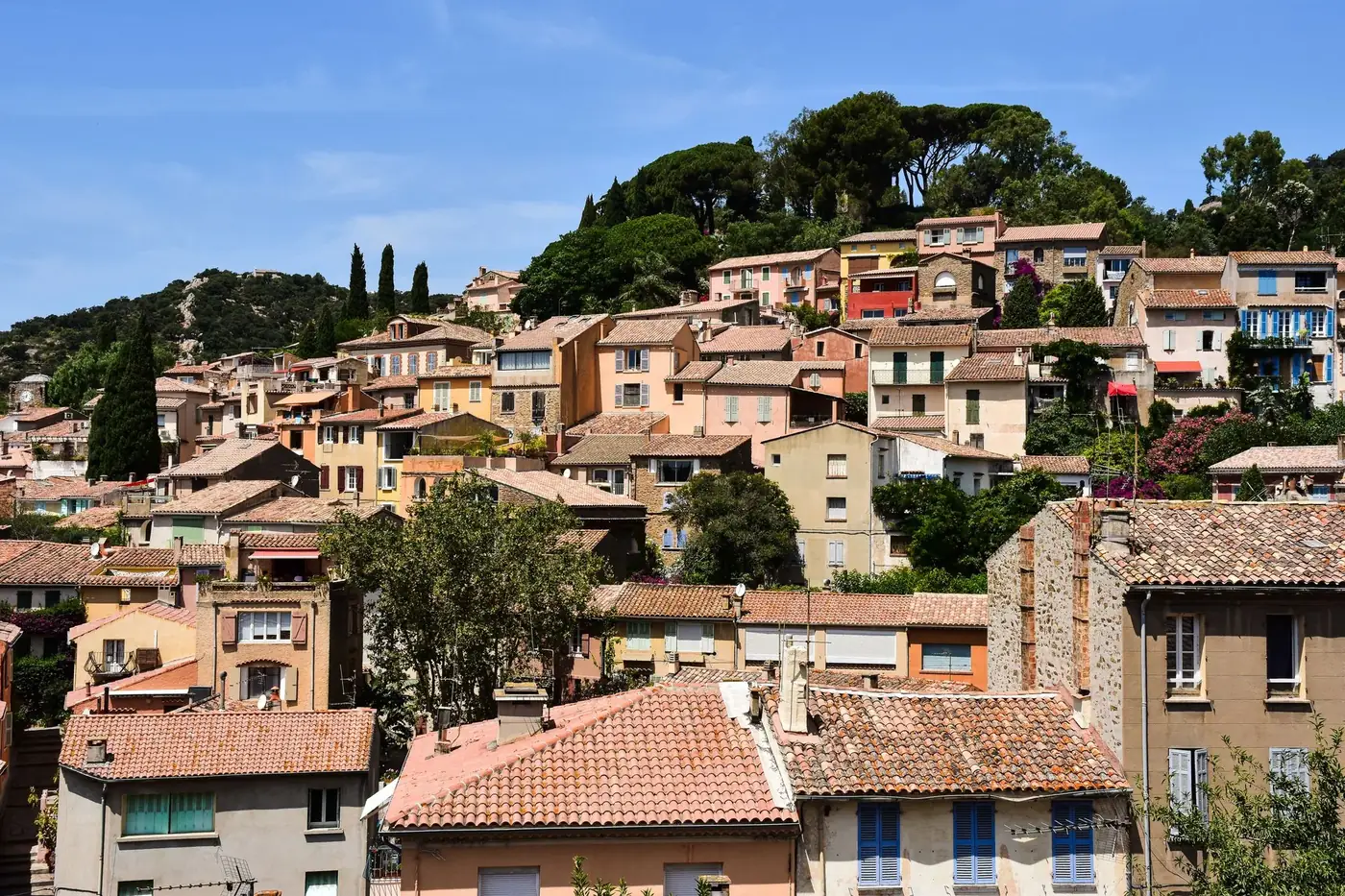 Charming hillside view of colorful houses in Bormes-les-Mimosas, France, under a clear blue sky.