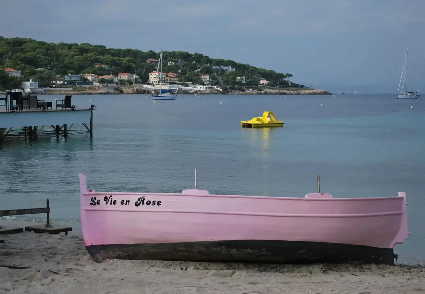 A charming pink boat titled 'La Vie en Rose' on a serene Antibes beach.