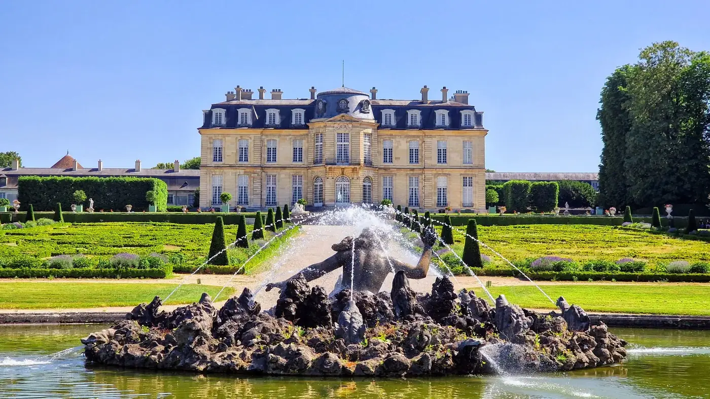Explore the stunning gardens and architecture of Château de Champs-sur-Marne during a bright summer's day.