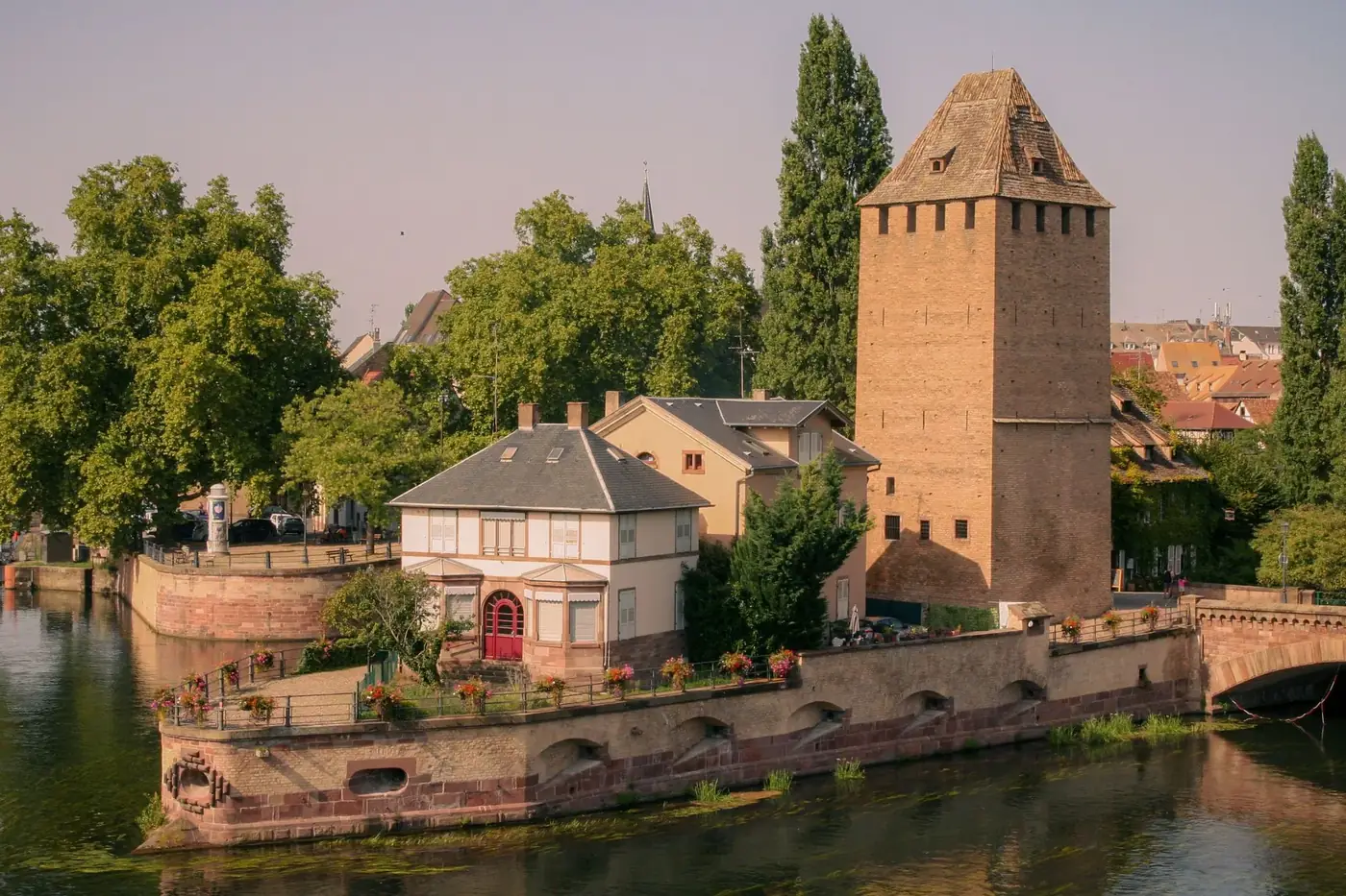 Beautiful view of a medieval tower and garden by the water in Strasbourg.
