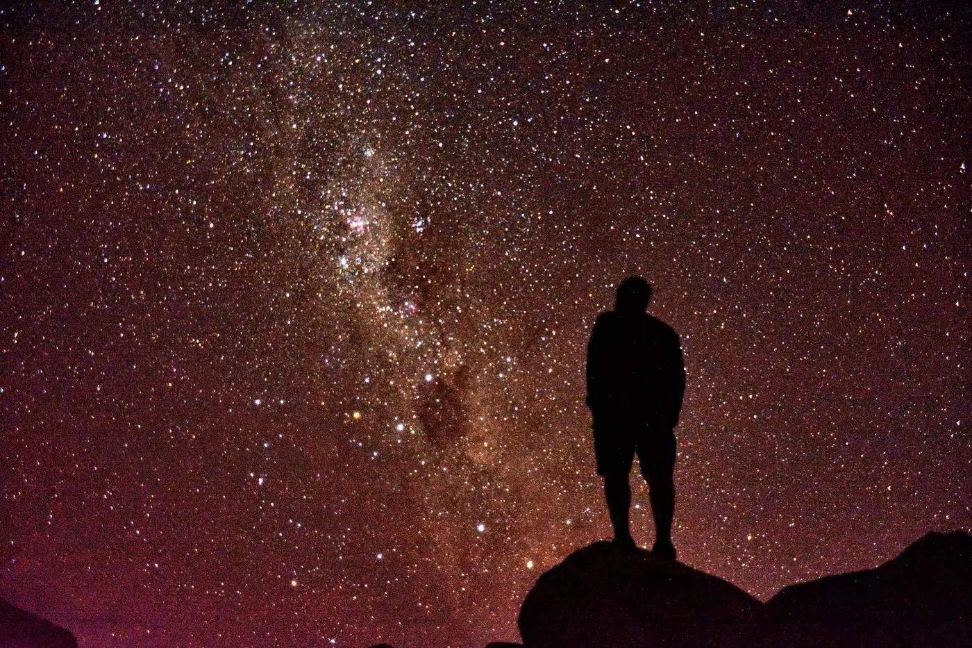 A person silhouetted against the starry night sky observing the Milky Way in New Zealand.