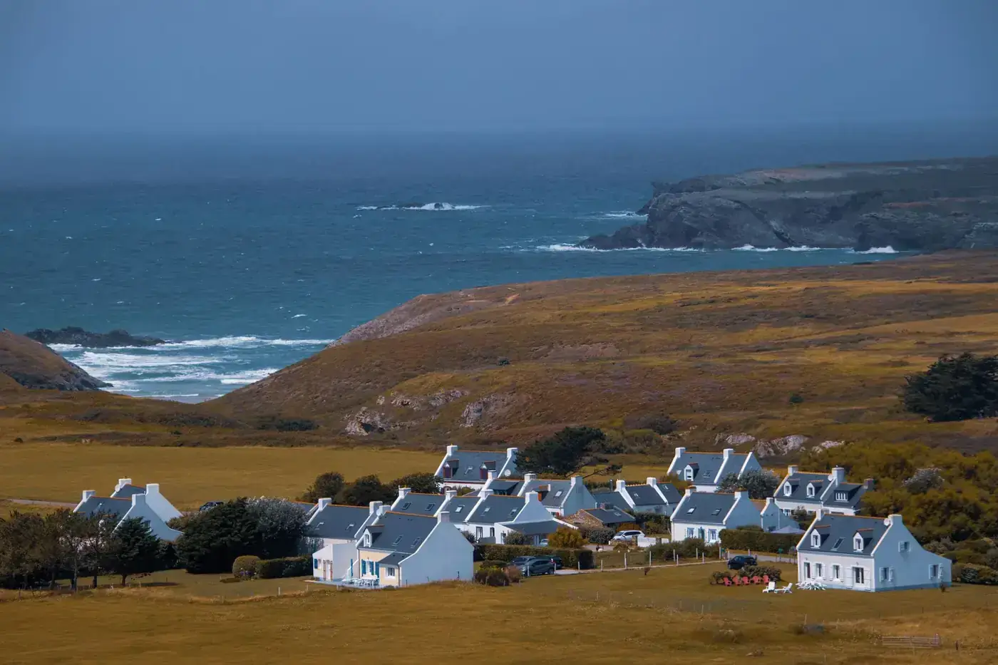 A serene view of a picturesque village along the Brittany coast in France, overlooking the sea.