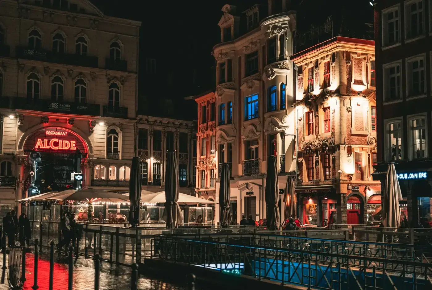 Experience the vibrant nightlife of Lille's historic architecture illuminated in warm lights.