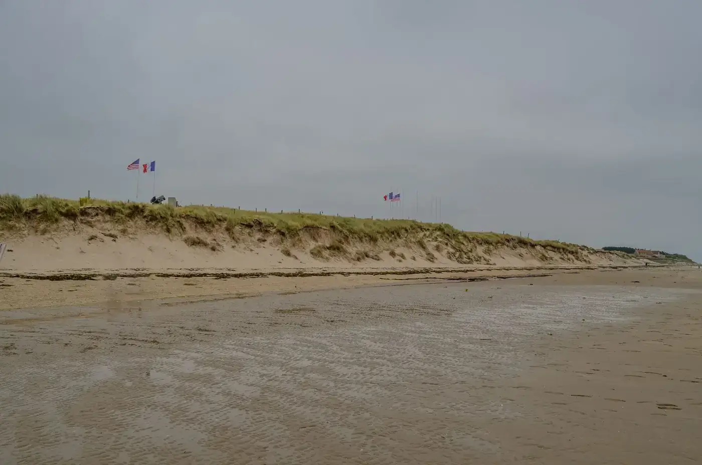 A historic view of Utah Beach in Normandy, France, with American and French flags symbolizing liberation.