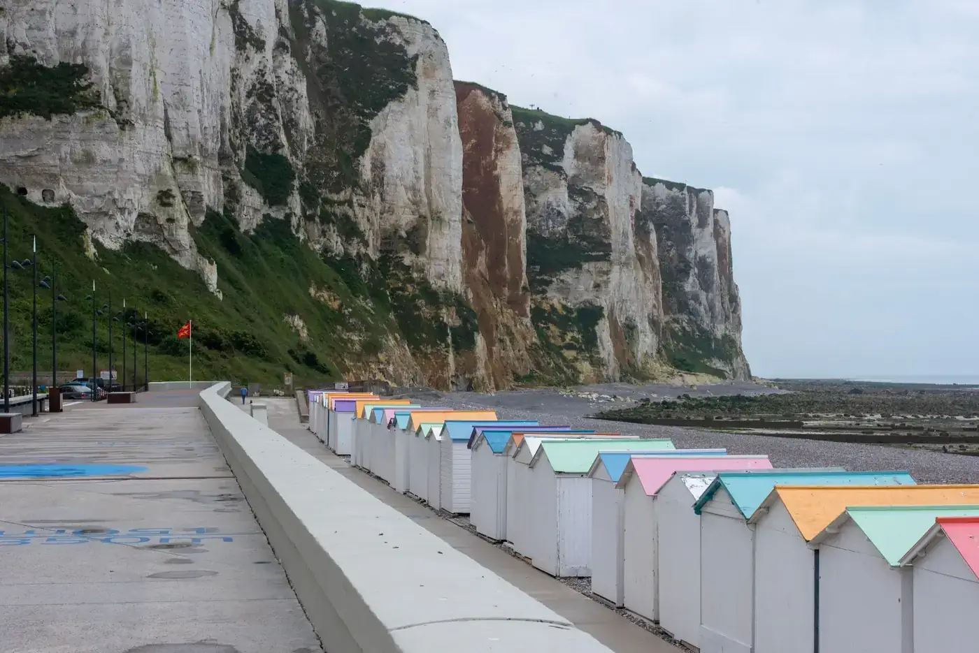 Vibrant beach huts line the promenade with stunning cliffs in Le Tréport, Normandy, France.