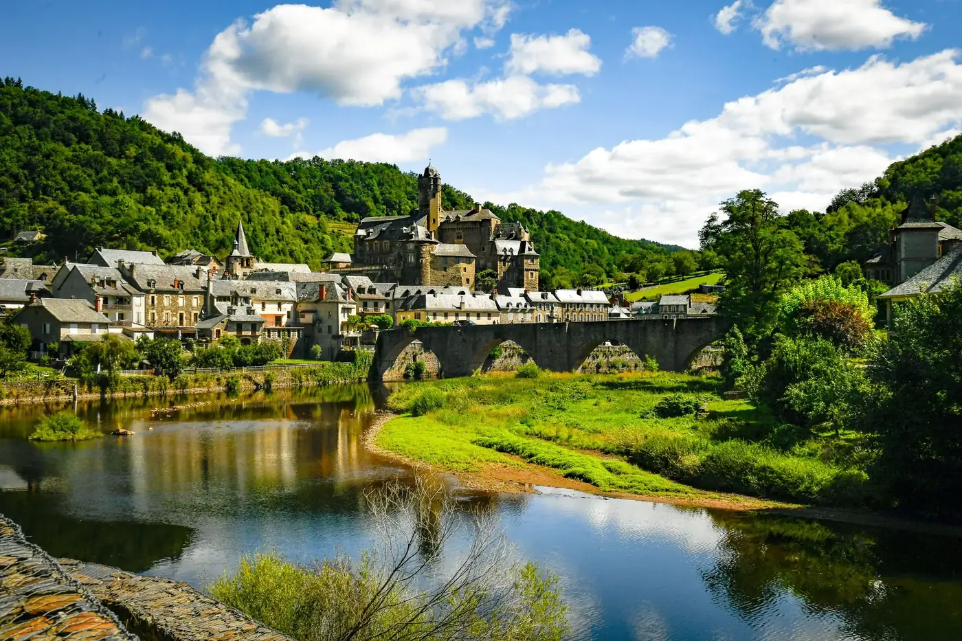 Explore the picturesque village of Estaing and its historic castle surrounded by lush greenery and a serene river.