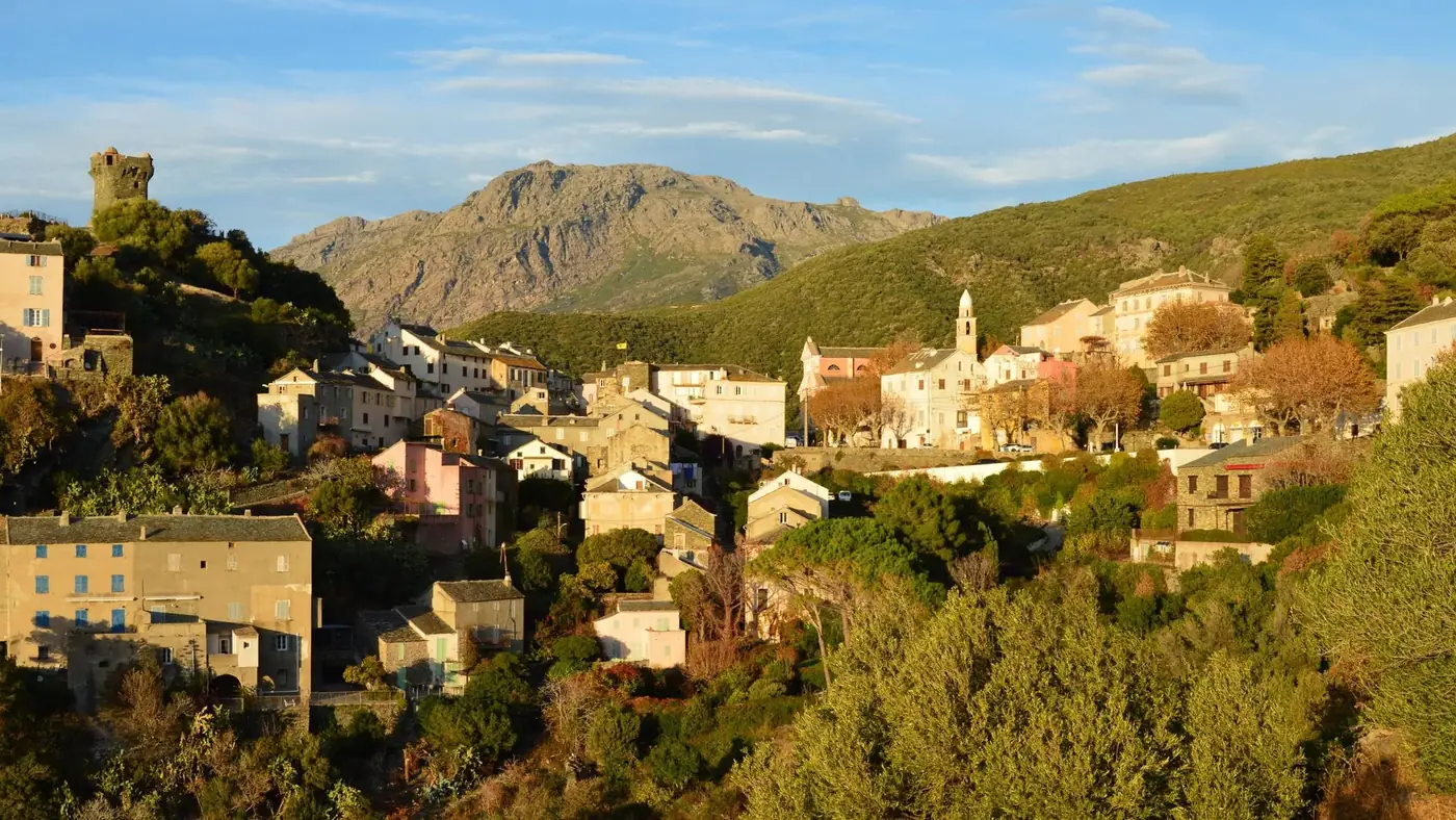 Picturesque view of Nonza village in Corse, France with mountains and traditional houses.