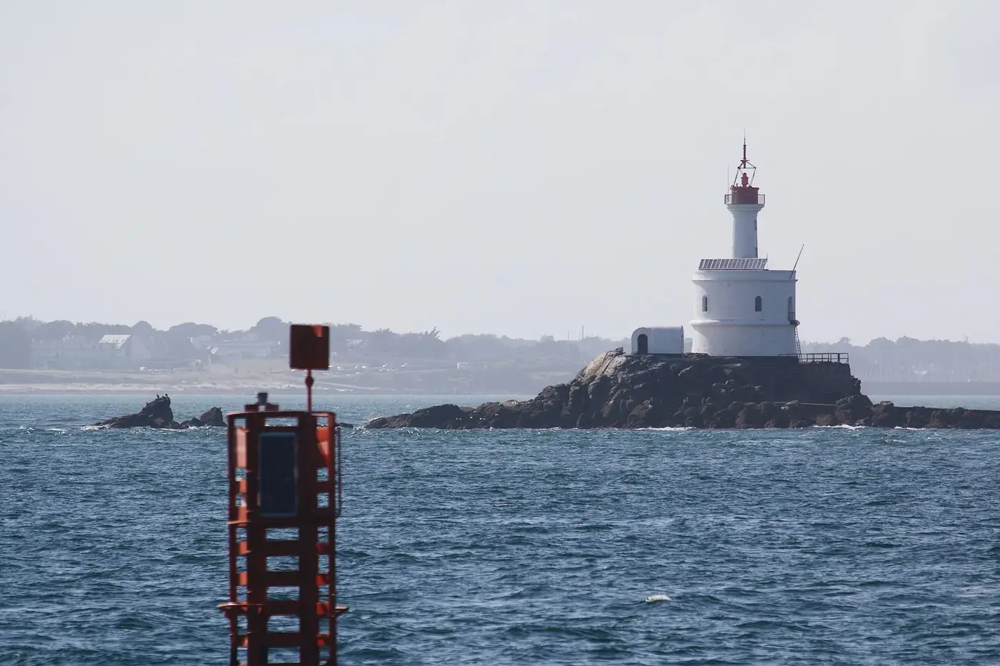 A picturesque lighthouse stands on rocky shores in Bretagne, France, guiding seafarers across the ocean.