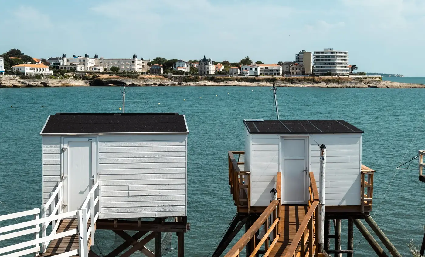 Scenic view of fishing huts over the sea with a charming French town in the background.