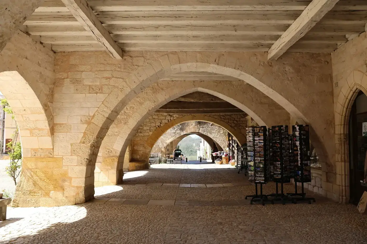Beautiful stone archway with shops and natural lighting in a historic setting.