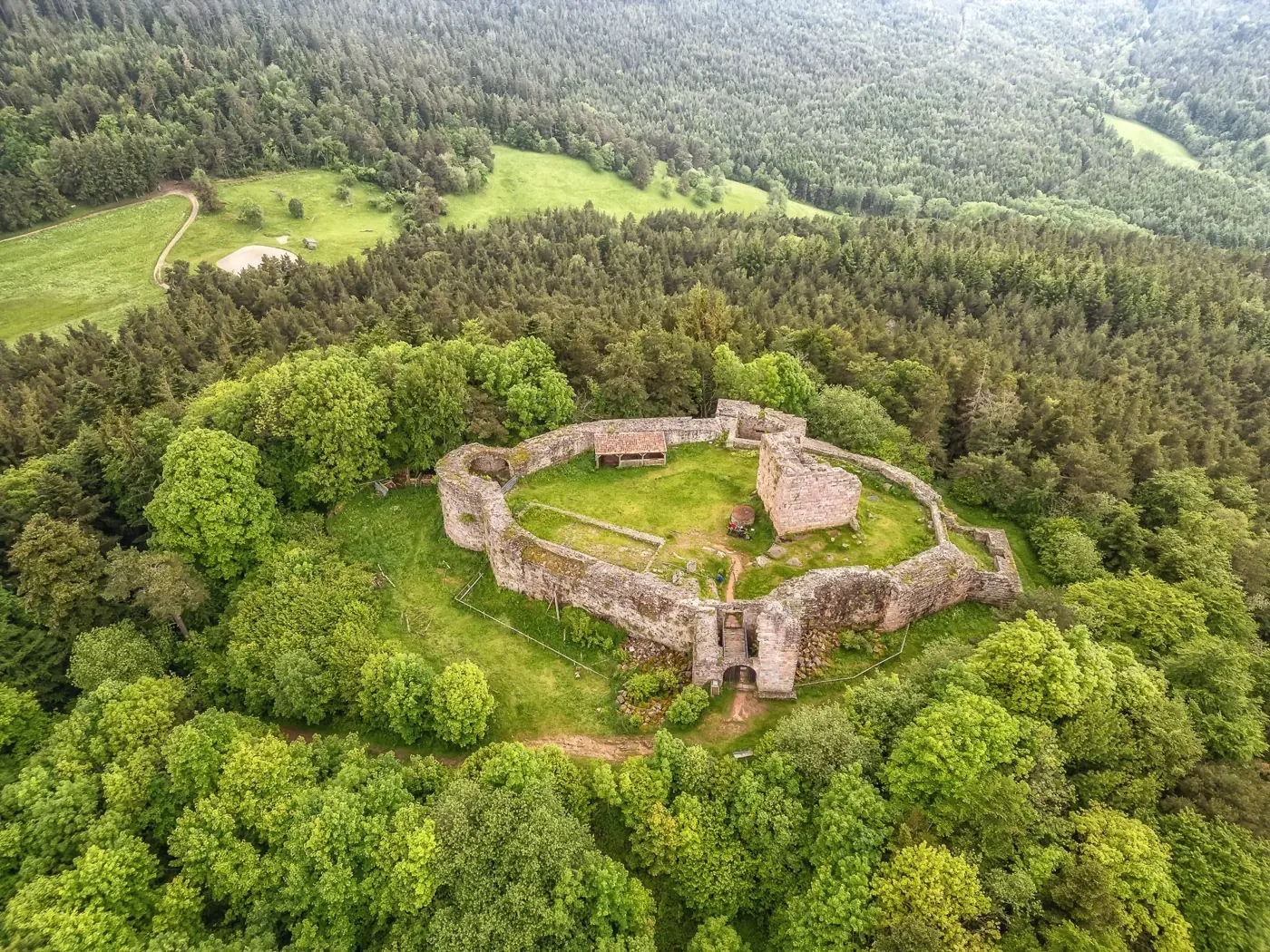 Drone shot of the historic Château du Hohnack, surrounded by lush forests in Alsace, France.