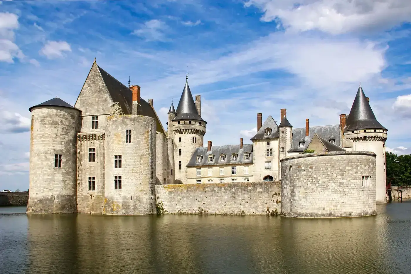 Majestic view of Sully-sur-Loire Castle reflecting in the moat under blue skies.