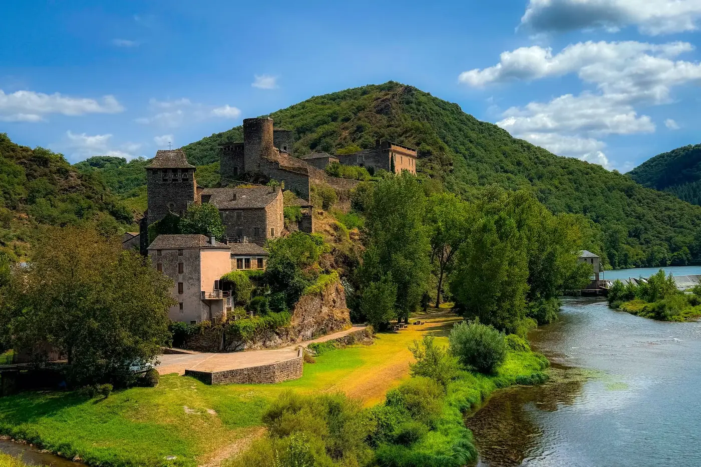 Beautiful summer view of Brousse-le-Château with surrounding nature and river.
